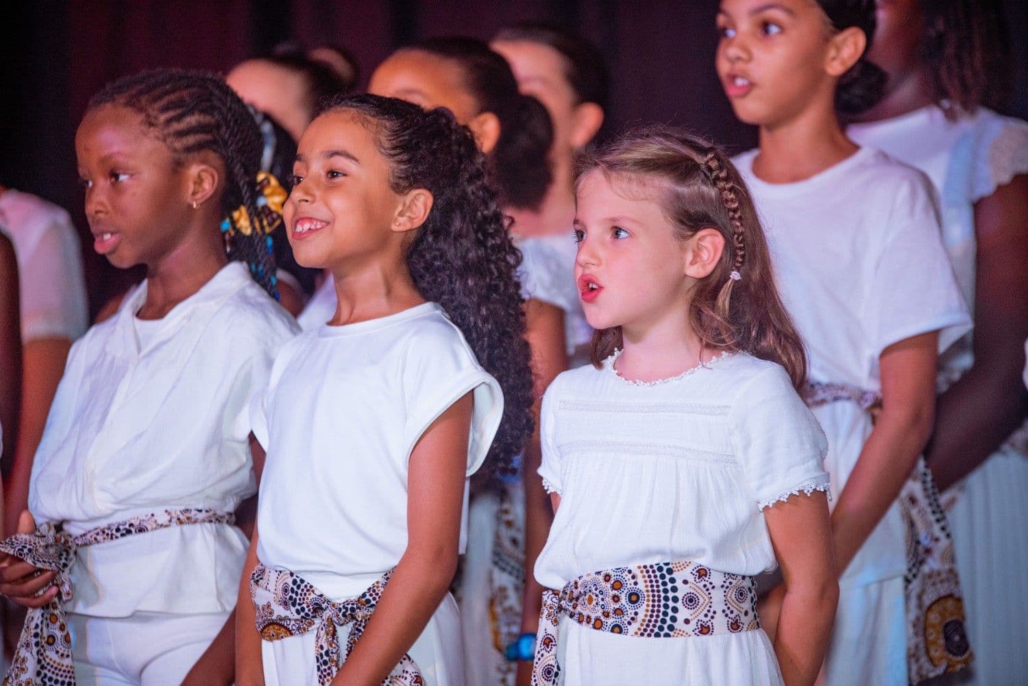 Young choir singers in white outfits performing at Christmas by Candlelight