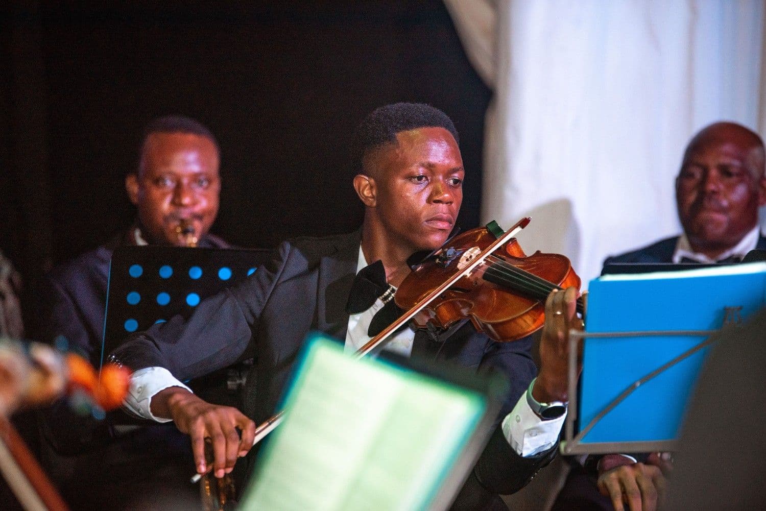 A violinist in a tuxedo playing with focused intensity