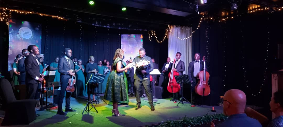Christmas by Candlelight stage with choir, strings, and festive lights
