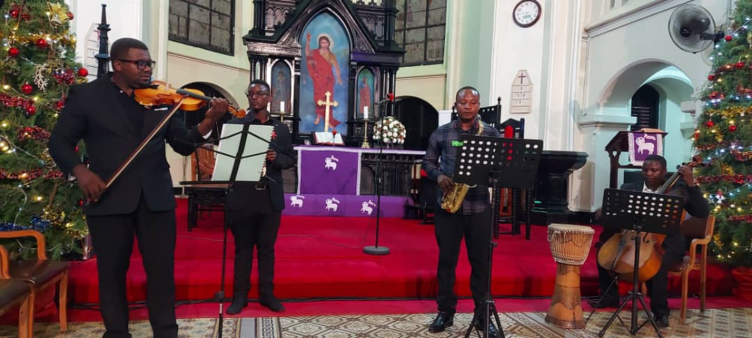 Chamber ensemble performing carols beside Christmas trees