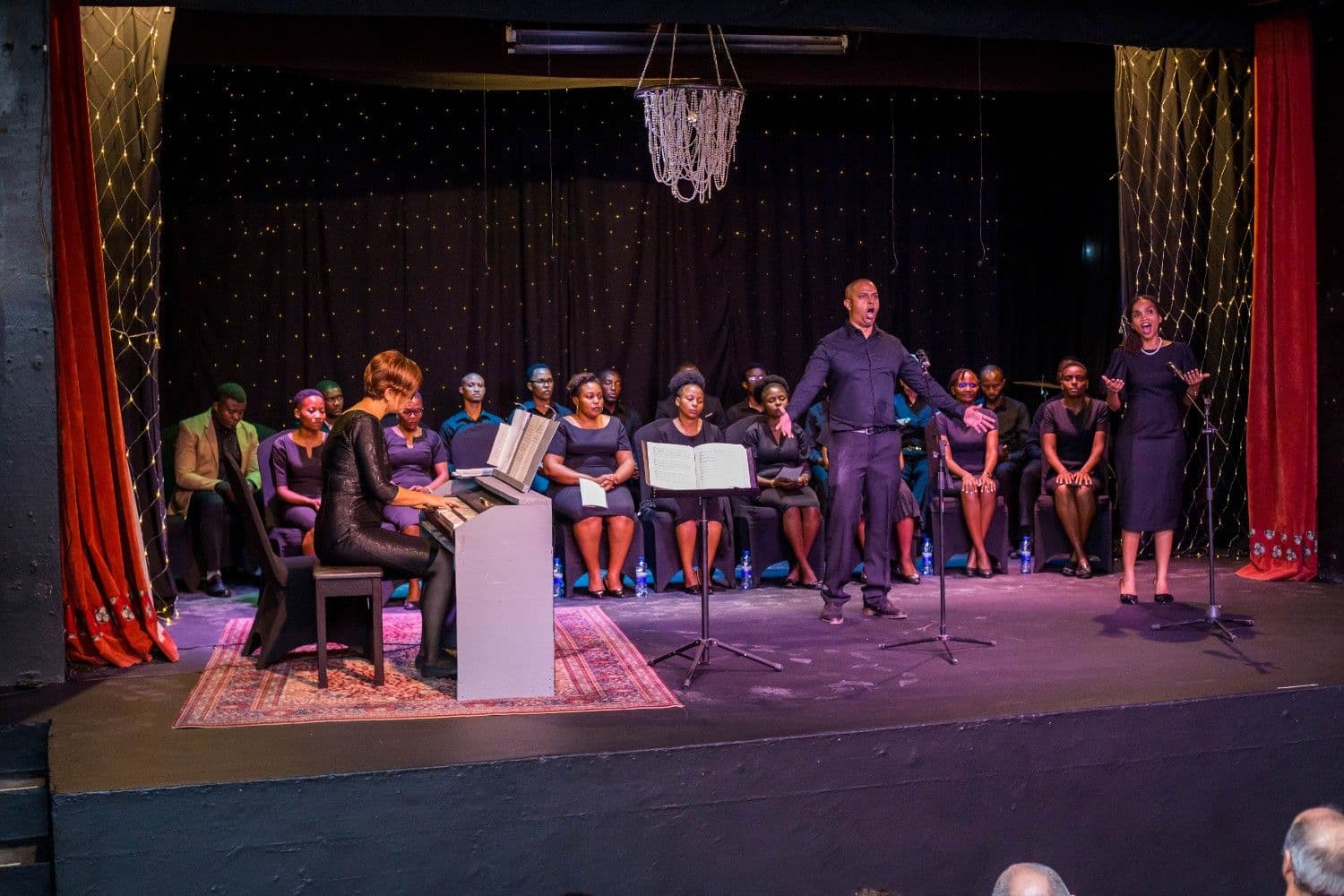 Soloists and choir under chandelier lights at Our Sound