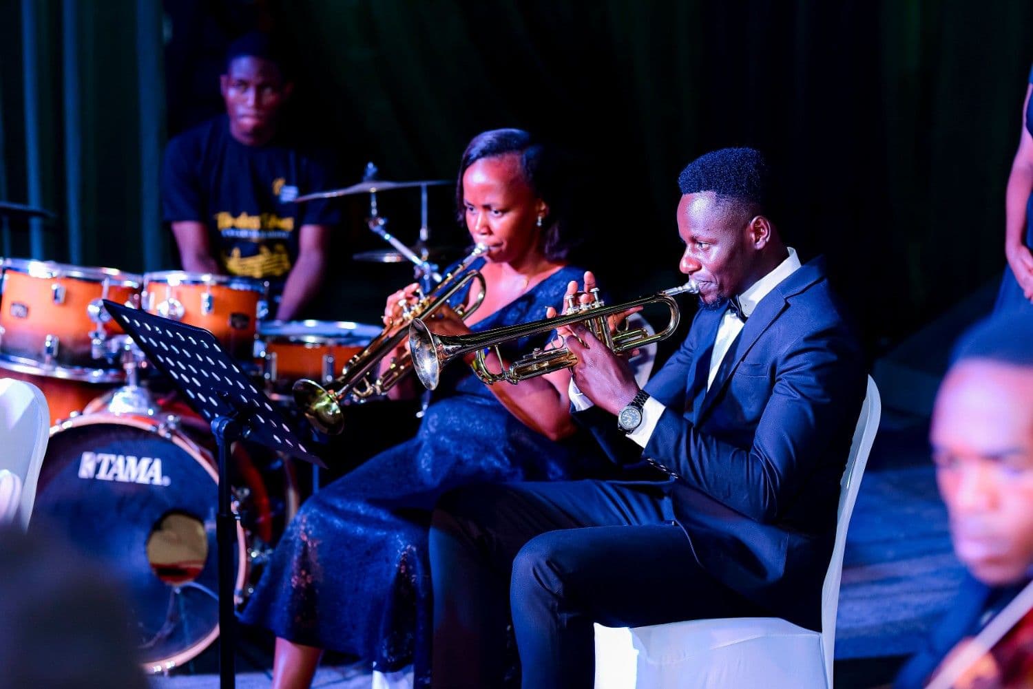 Trumpet players in tuxedo and gown with a drummer behind them