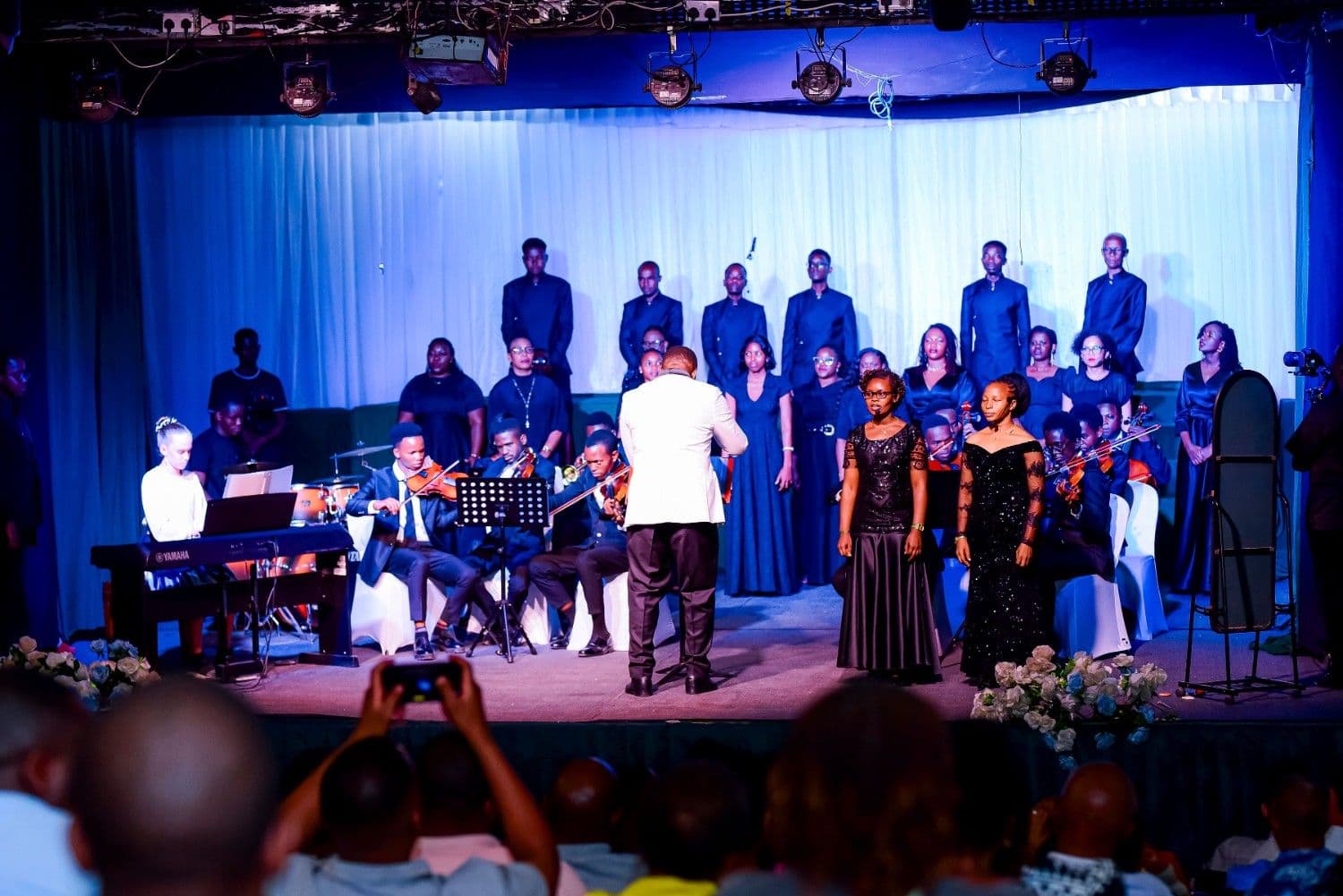 Timeless Echoes full ensemble with conductor, soloists, choir, and orchestra under blue lights