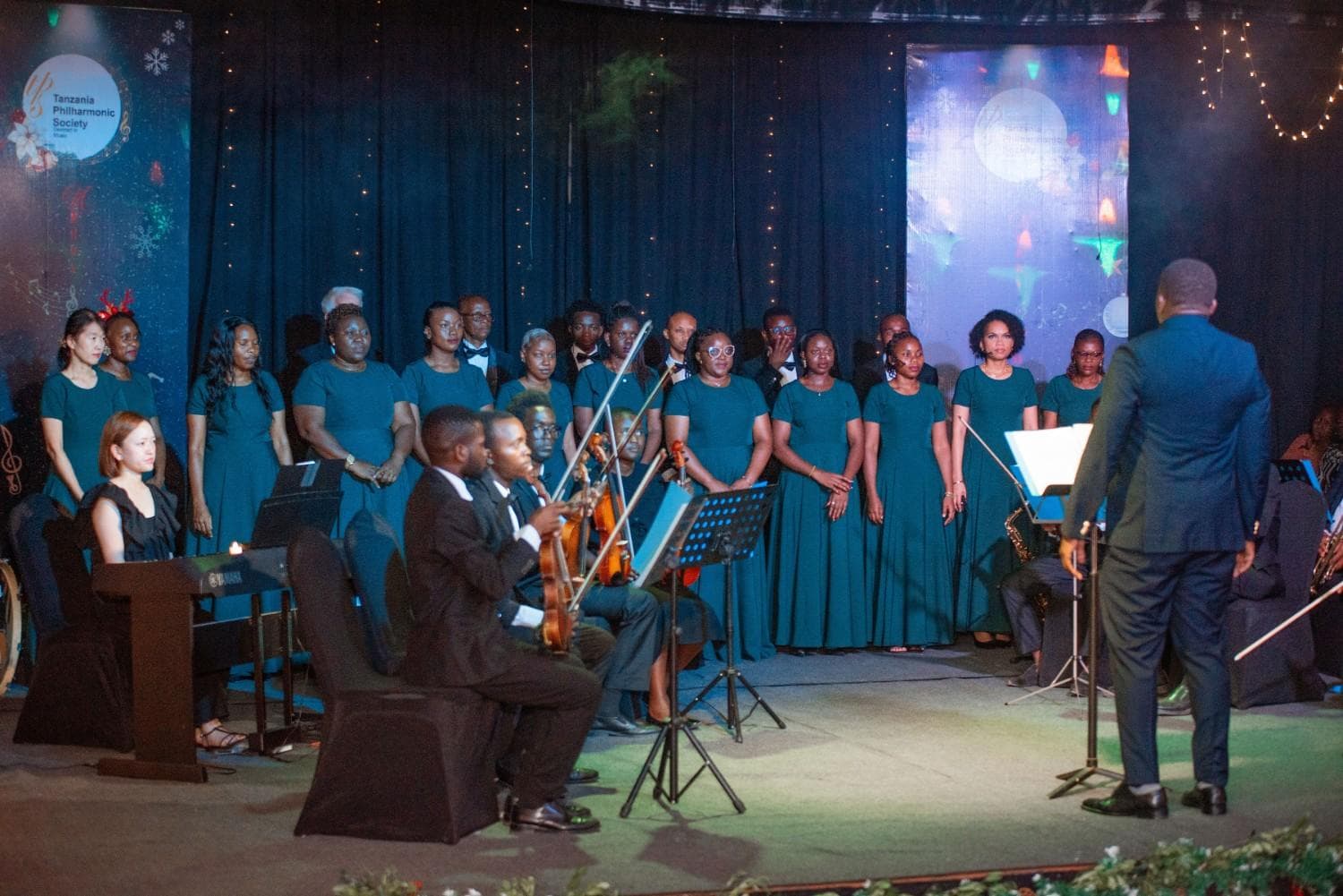 Christmas by Candlelight choir in emerald gowns with strings, piano, and fairy lights