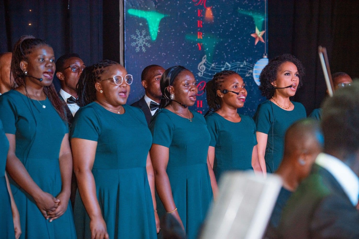Women in emerald gowns singing on the Christmas by Candlelight stage